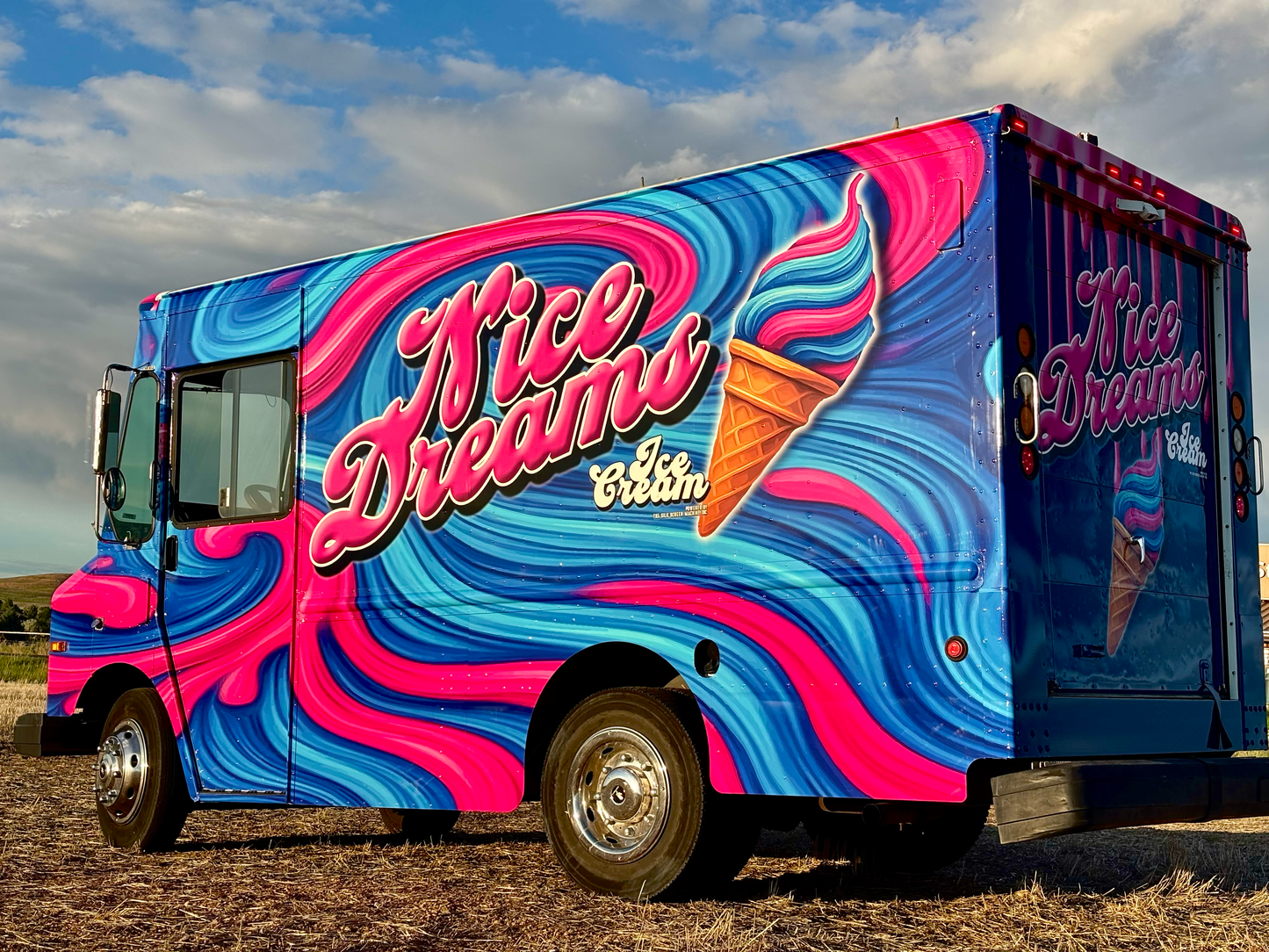 A picture of a vivid and bright ice cream truck that screen prints t-shirts named "Nice Dreams Ice Cream" and the paint job showcases blue and pink swirly background like melting ice cream.