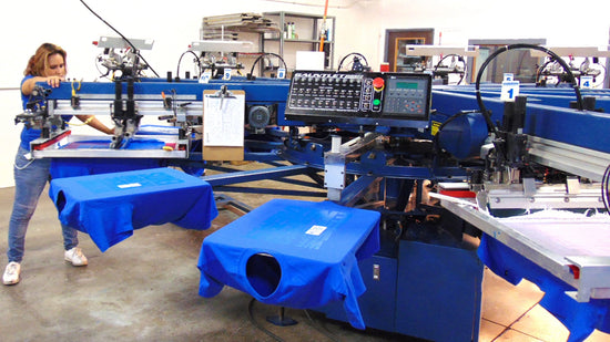 Lady running an automatic screen printing press with blue t-shirts in Denver and Boulder, Colorado