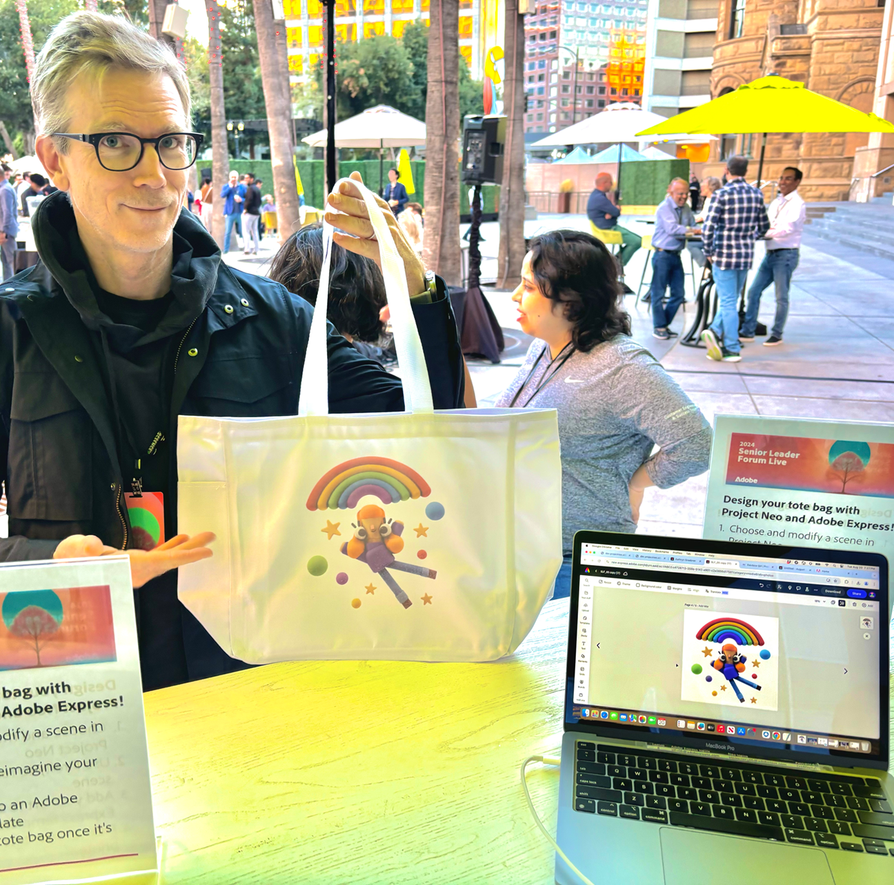 A man holding a tote bag that was just live printed in full color from an image on his phone at a live AirDrop Printing event showcasing  Adobe Express's Generative AI.