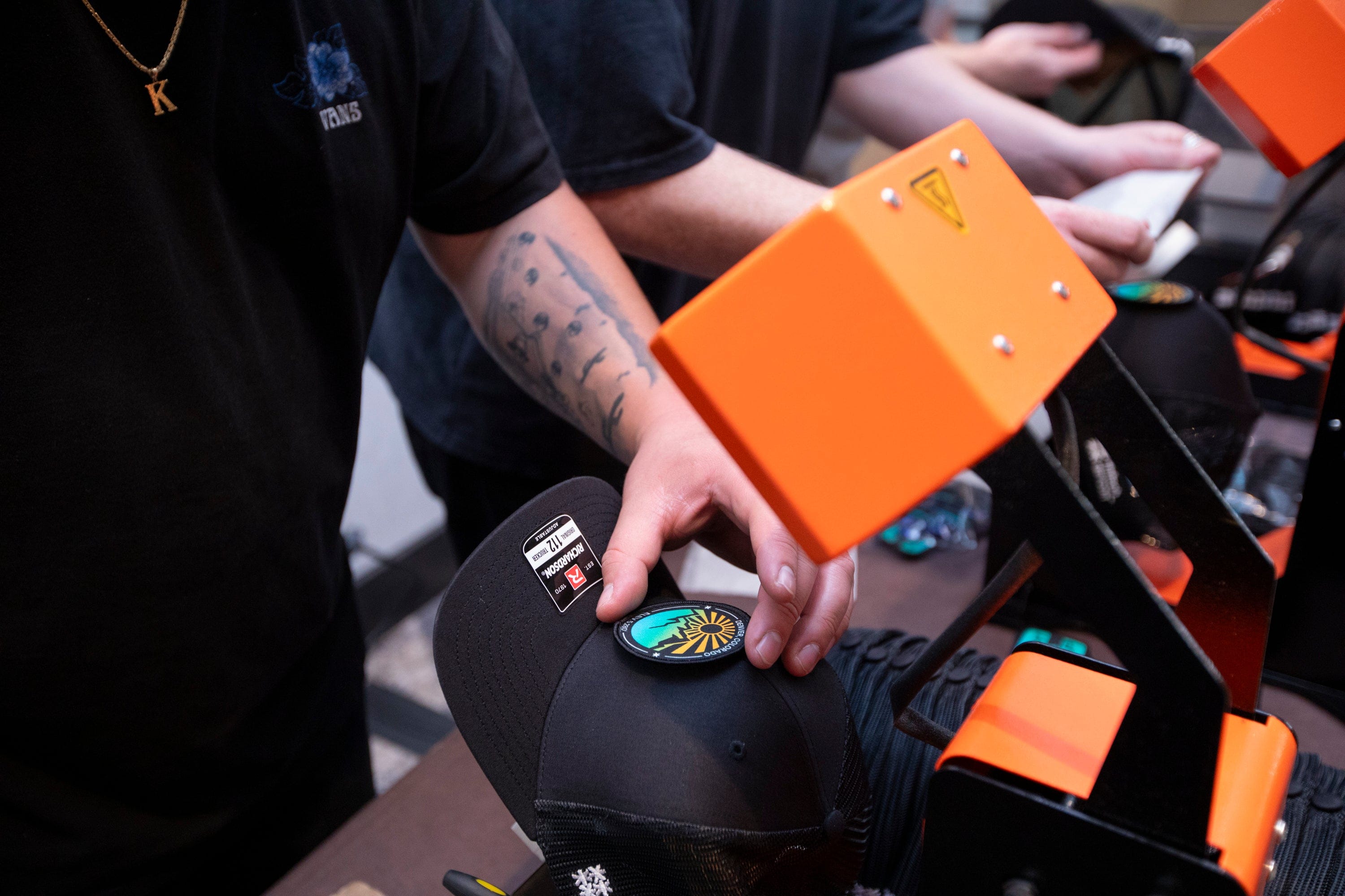 A live printing technician customizing a trucker hats at a large tech conference in Denver, Colorado for a custom onsite hat bar experience.