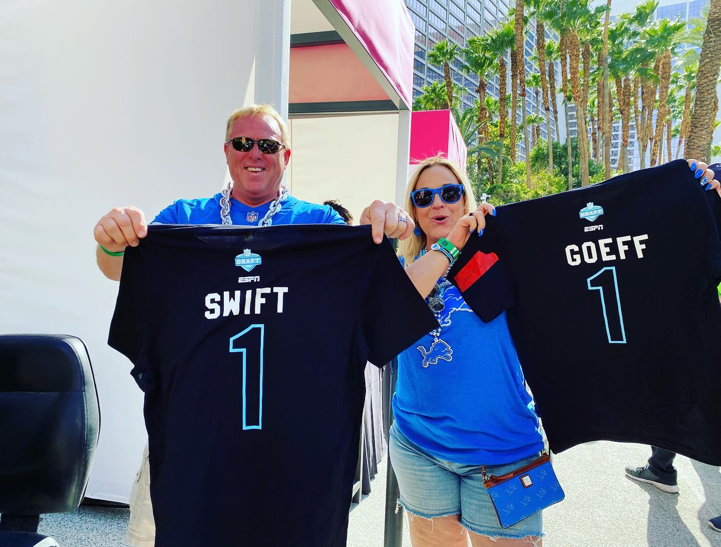 A couple holding up shirts that were just Live Screen Printed with custom names at a live customization event for ESPN and the NFL draft in Las Vegas pool party event.