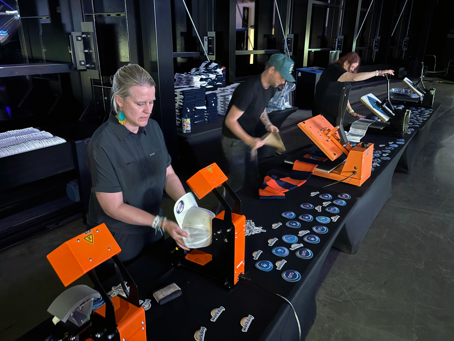 A team of live screen printers a customizing hats with patches that guests of a corporate event chose at Allegiant Stadium where the Raiders NFL team play in Las Vegas, Nevada.