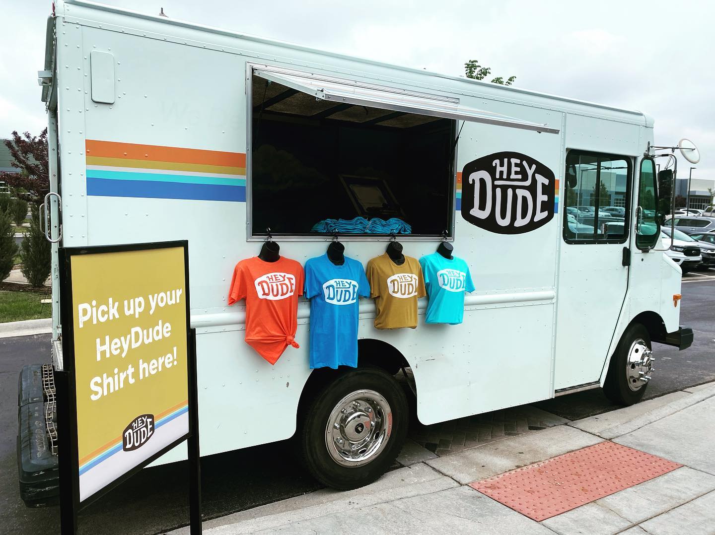 A picture of a vivid and bright ice cream truck that also screen prints t-shirts named "Nice Dreams Ice Cream" and the paint job showcases blue and pink swirly background like melting ice cream.