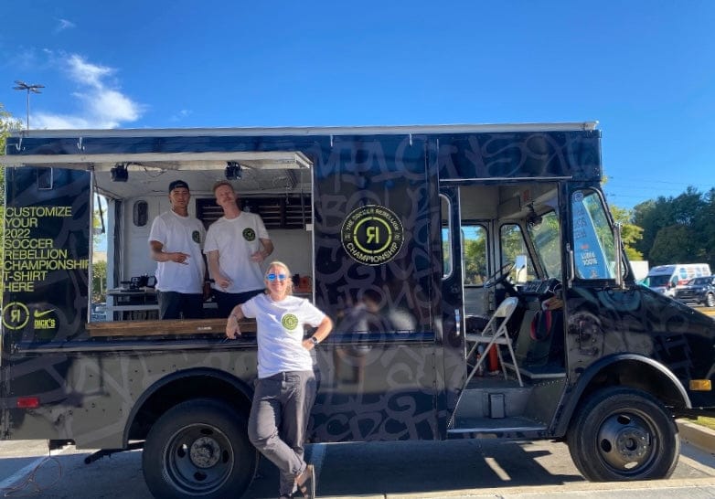 Three onsite mobile print technicians at a large sporting event customizing promotional merchandise LIVE off of a mobile screen printing print and customization truck with a custom vinyl wrap for Nike and Dick's Sporting Goods.  