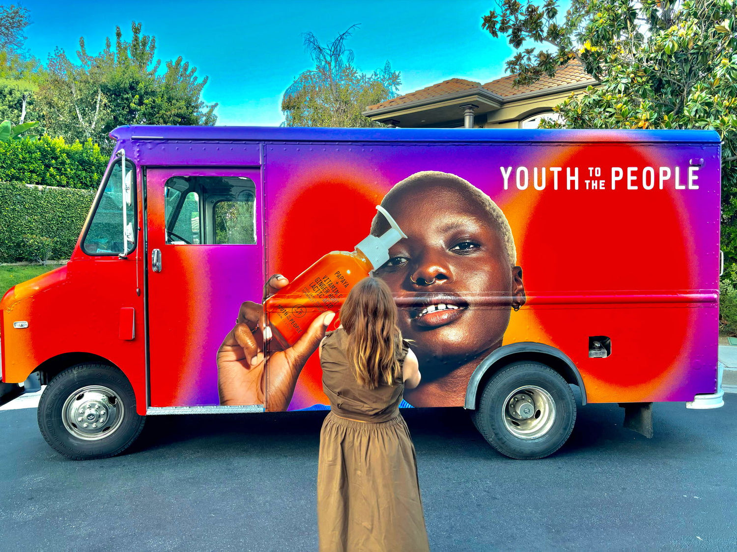 A healthy lady taking pictures of our mobile promotional billboard vehicle that travels around Los Angeles, CA distributing samples to social media influencers with an eye catching vinyl vehicle wrap that.