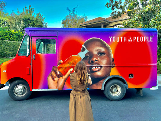 A mobile billboard truck in Los Angeles with a vibrant vinyl wrap for a brand marketing and advertising campaign and a very excited guest taking pictures of the truck.