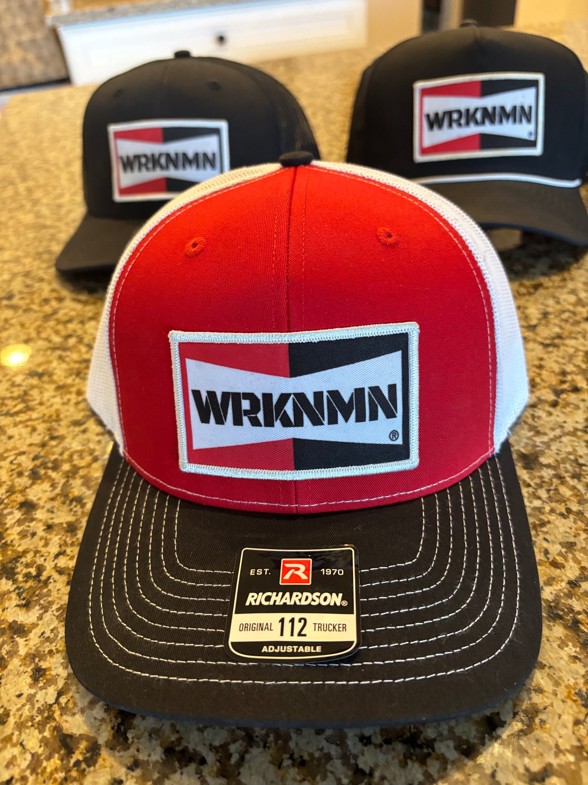 A red and black WRKNMN vintage retro trucker hat on display.