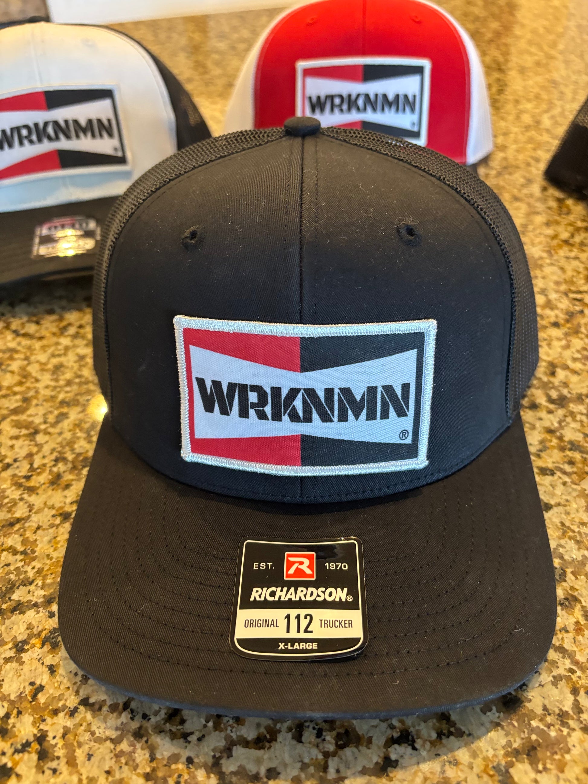 Black cap with WRKNMN logo on a granite surface