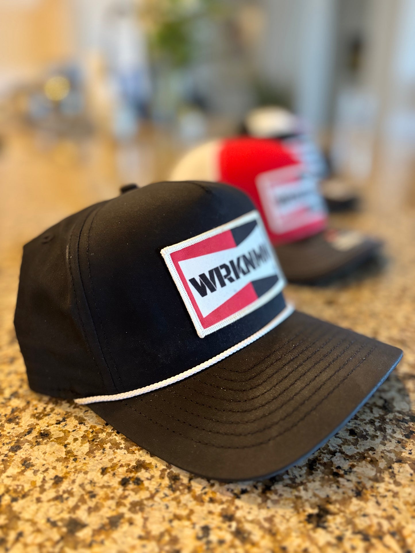 Black cap with a red and white WRKNMN logo on a blurred background